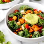 Close up of a southwestern chicken salad in a white bowl with avocado dressing on top.